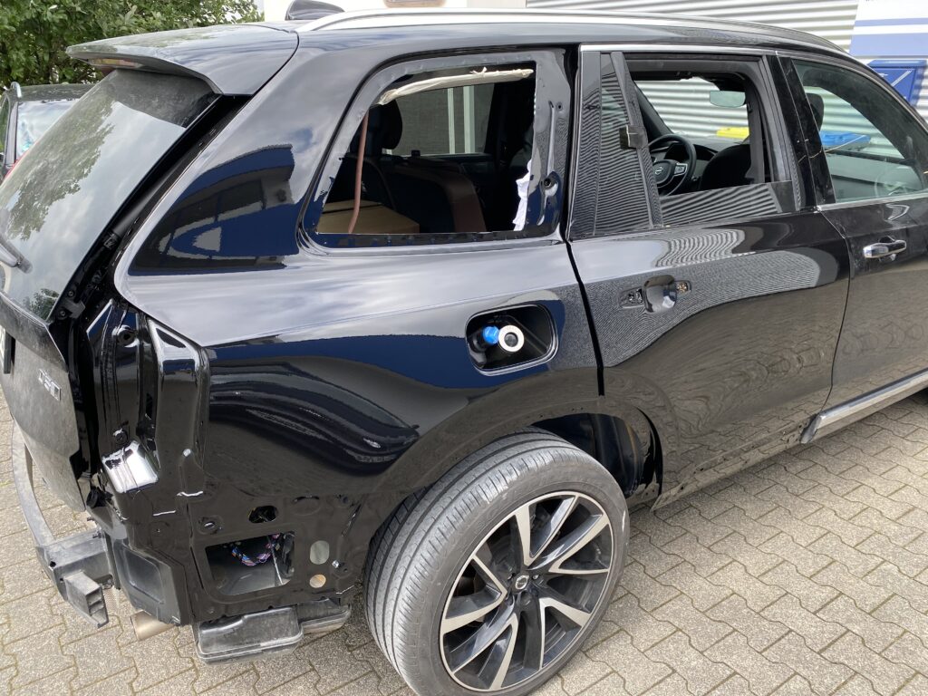 Schwarzer SUV mit ausgebauten hinteren Seitenscheiben und beschädigter hinterer Karosserie auf Pflasterstein