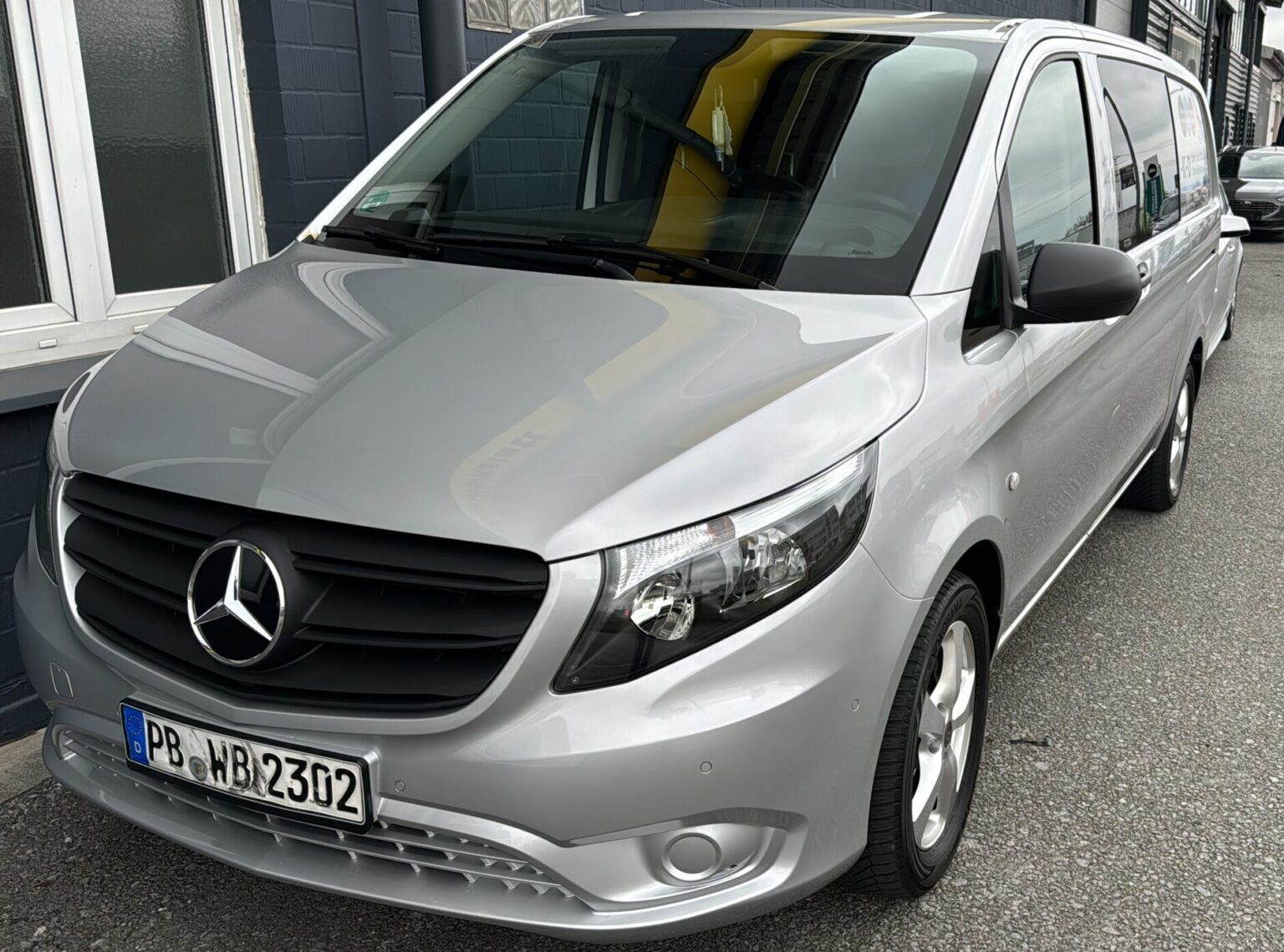 Silberner Mercedes-Van mit großem Kühlergrill und deutschem Kennzeichen vor einem Gebäude geparkt