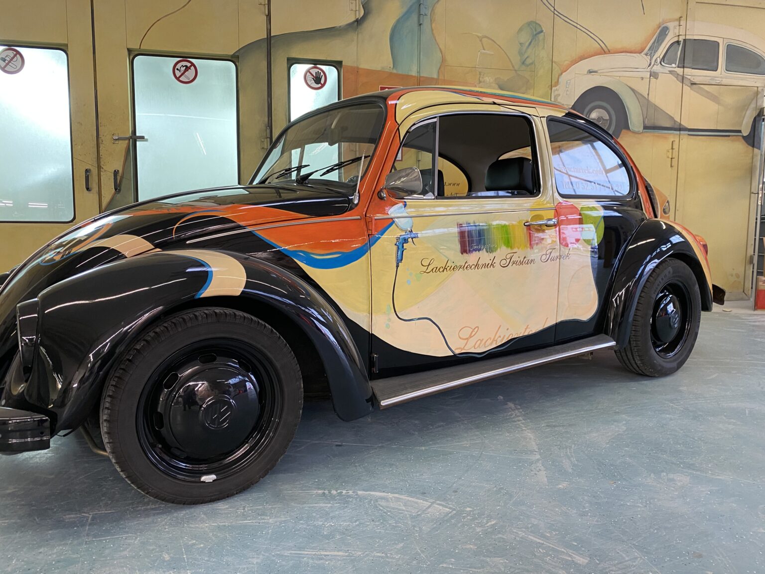 Bunt lackierter VW Käfer in einer Werkstatt mit kunstvoller Karosseriebemalung