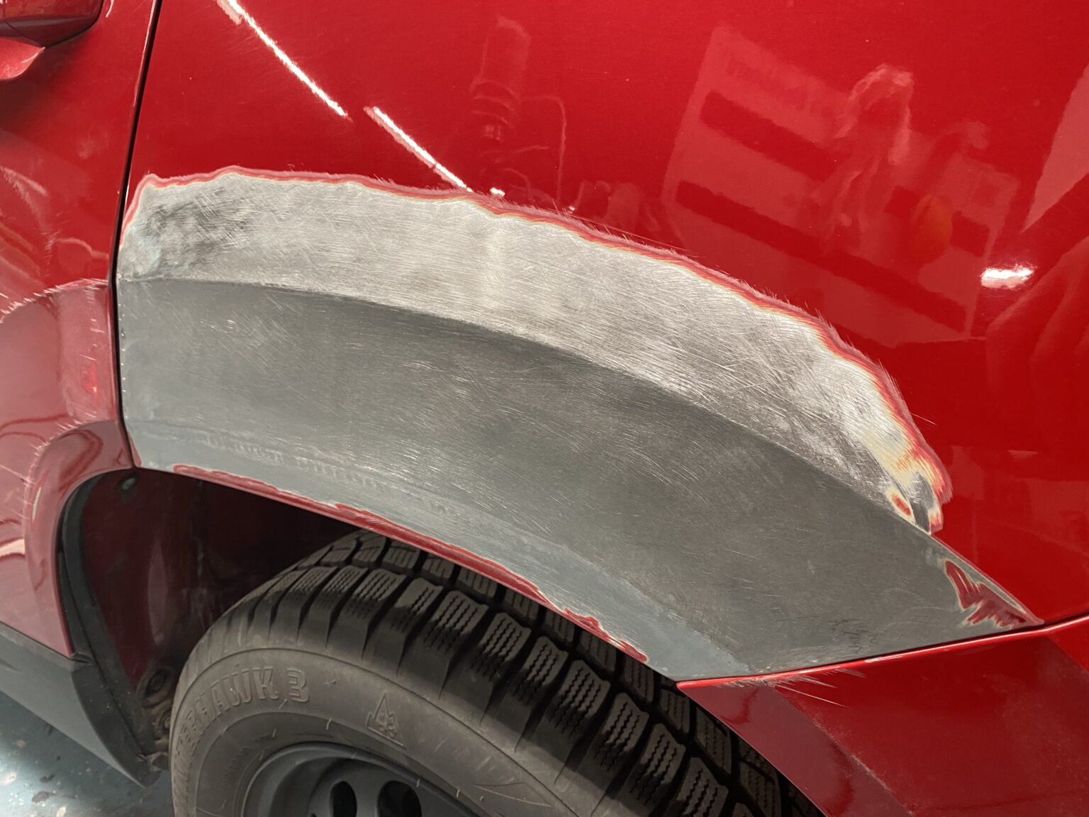 Roter Autolack mit angeschliffener und gespachtelter Stelle am hinteren Radlauf