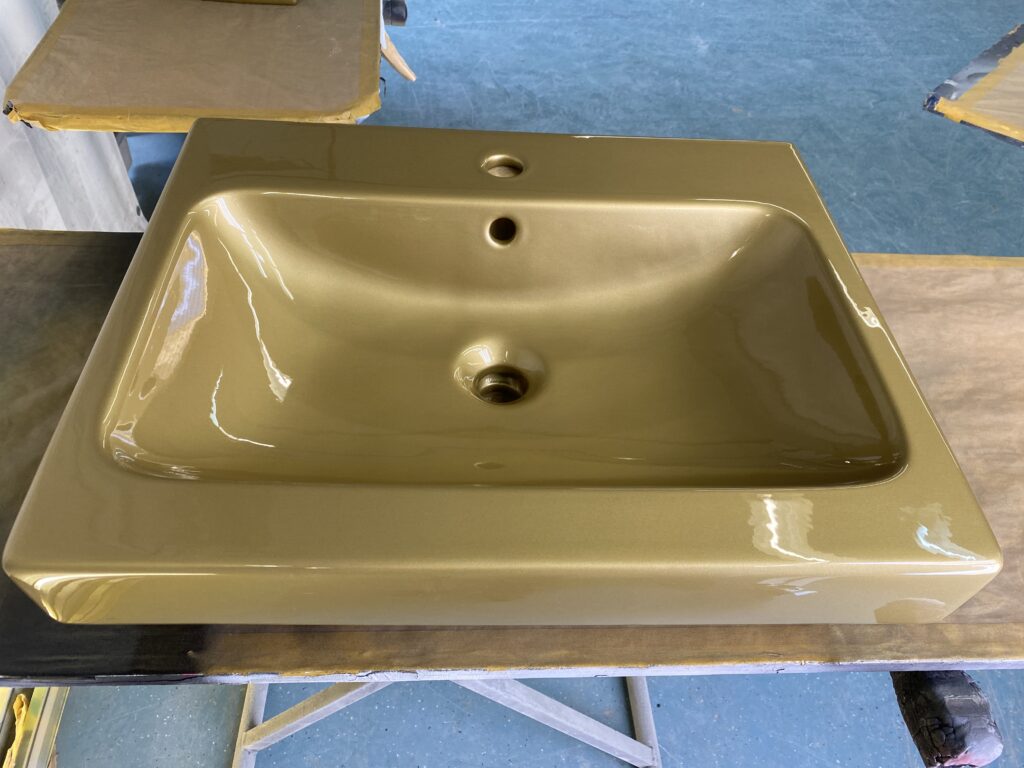 Goldfarbenes Waschbecken aus Keramik mit Loch für Armatur auf einer Werkbank