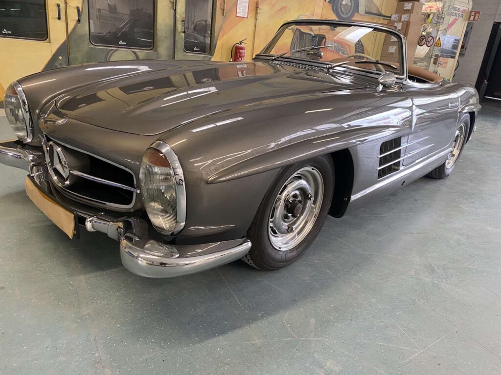 Grauer Mercedes-Benz 300 SL Roadster in einer Werkstatt, Frontansicht von schräg vorne